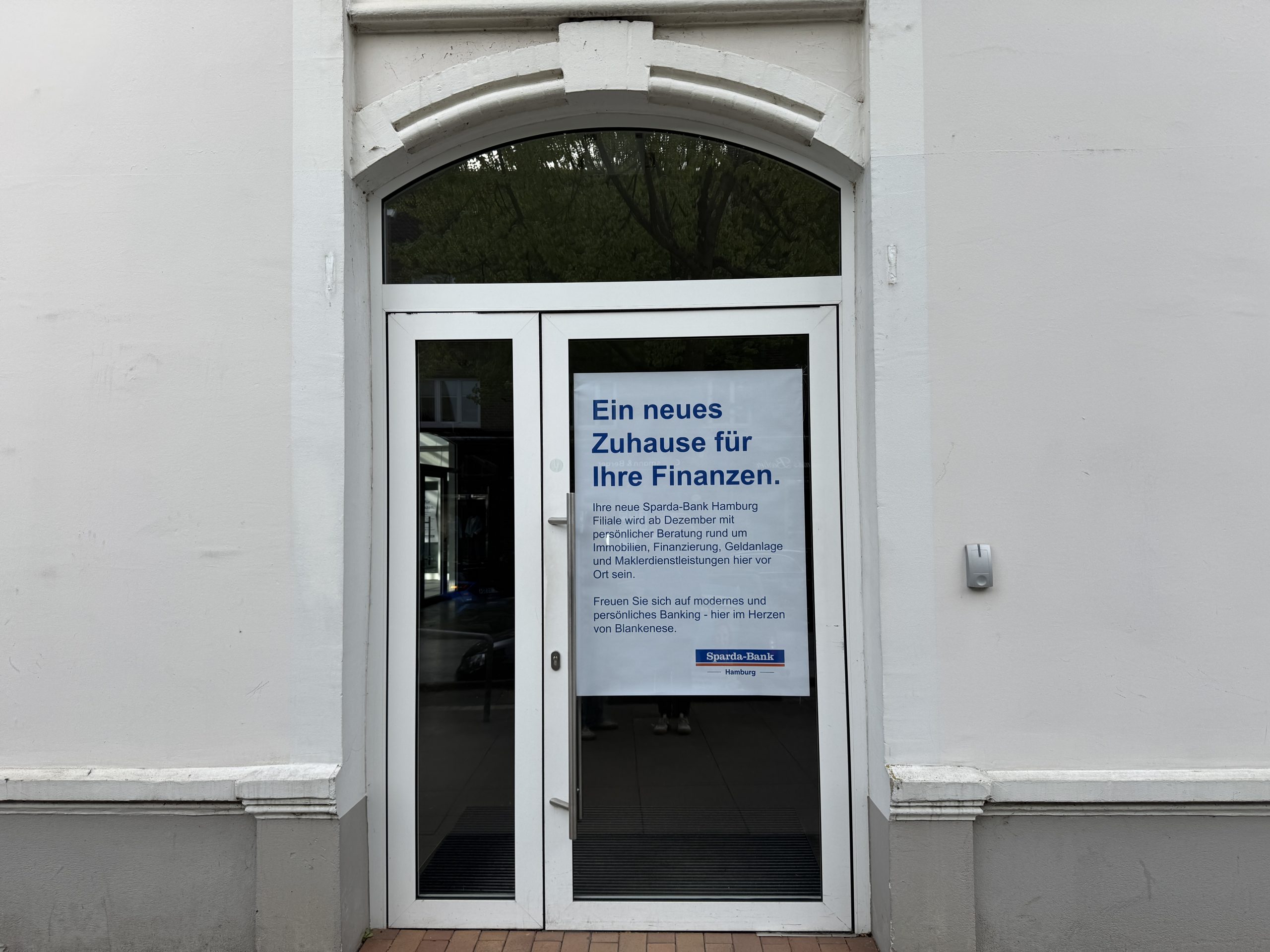 Ein Plakat an einem Ladengeschäft zeigt an, dass da demnächst eine Bankfiliale eröffnet.